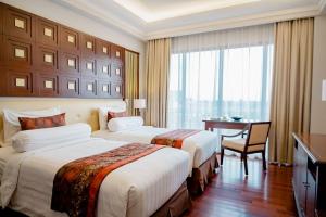 a hotel room with two beds and a desk at The Sunan Hotel Solo in Solo