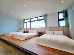 two beds in a room with two windows at Yours Inn Luodong in Luodong