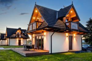 a house with a pitched roof with a patio at Korona Gór - Domki Białka Tatrzańska in Białka Tatrzanska