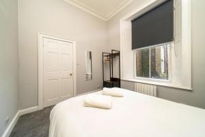 a bedroom with a white bed with a window at Lochside Apartments, Apt B in Montrose