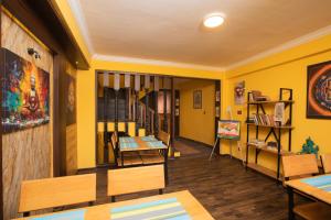 a room with yellow walls and wooden tables and chairs at La Dimora Homestay in Kirtipur +4 photos