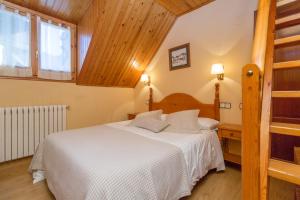 - une chambre avec un lit blanc et un plafond en bois dans l'établissement Hostal Casa Rosita, à Eriste