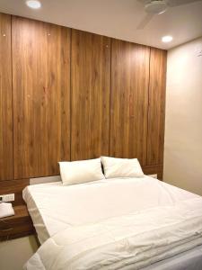 een slaapkamer met een groot wit bed met houten lambrisering bij RadhaKrishna Executive in Tuljapur +32 foto's