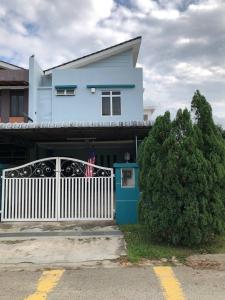 a blue house with a white fence in front of it at Pulai Bliss Homestay in Pekan Nanas