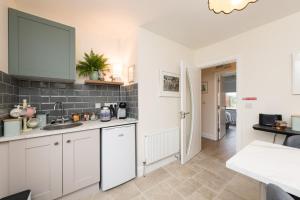 a kitchen with white cabinets and a sink at Foxglove House in Douglas