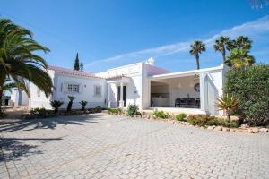 a white house with palm trees and a driveway at Pomba beautifully renovated with heated pool! in Poço Partido