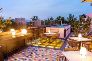 un patio all'ultimo piano con tavoli, sedie e piscina di Hotel Luciano K a Santiago