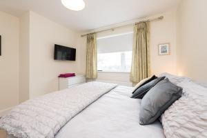 a bedroom with a white bed and a window at Foxglove House in Douglas