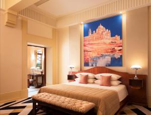 a bedroom with a large bed with a painting on the wall at Umaid Bhawan Palace Jodhpur in Jodhpur