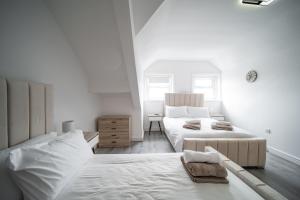 a white bedroom with two beds and a couch at Spacious Duplex Apartment - Perfectly Situated in the Heart of the City in Blackpool