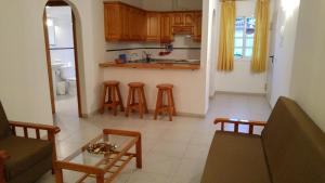 a living room with a couch and a kitchen with stools at Apartamentos Martell in Playa de Santiago