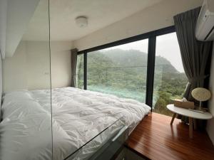 una camera da letto con un letto e una grande finestra di vetro di 礁溪好好沐包棟溫泉Villa 龜山島景觀 客餐廳可開伙 KTV Netflix 禁菸 戶外平面停車 a Jiaoxi