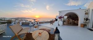 a sunset over the ocean from a house with a table and chairs at Vougli View Mykonos in Drafaki