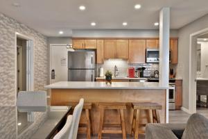una cucina con armadi in legno e un bar con sgabelli di Spacious 2RM-2BA Condo in the Heart of the Town, Summer Pool, Shuttle Route a Killington