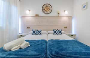 two beds in a bedroom with a clock on the wall at El Nogal Home in Málaga