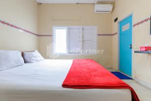 een slaapkamer met een bed met een rode deken erop bij Arwana Inn Syariah Lampung Mitra RedDoorz in Bandar Lampung