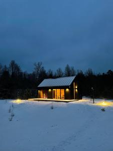 a small house in a snowy field at night at Forestic Lietuva in Vilionys