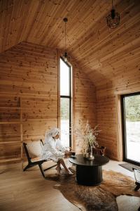 a woman sitting on a chair in a room with a table at Forestic Lietuva in Vilionys
