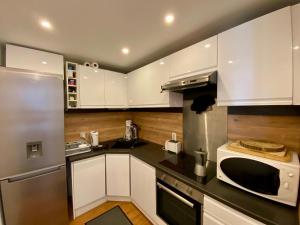 een keuken met witte kasten en een magnetron bij Appartement 8 personnes 3 chambres 1 750 m altitude in Chamrousse +6 foto's
