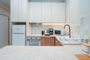 una cucina con mobili bianchi e un frigorifero bianco di Koukaki Jacuzzi Retreat ad Atene Altre 29 foto
