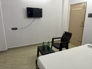 a room with a bed and a chair and a television at Rest N' Refresh Homes in Visakhapatnam