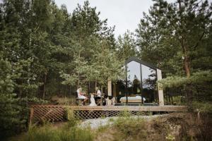 two people and two dogs sitting in a glass house at Forestic Lietuva in Vilionys