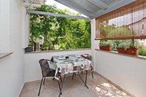 una mesa y una silla en un balcón con ventana en Apartments Karamarko, en Baška