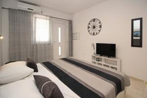 Un dormitorio con una cama y un reloj en la pared. en Apartments Karamarko, en Baška
