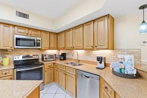 a kitchen with wooden cabinets and a sink at Bluewater 402 in Orange Beach