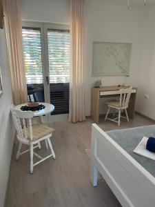 a room with a bed and a desk and a table and chairs at Baracuda in Veli Lošinj