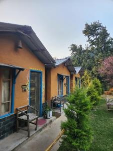 a house with a bench outside of it at Monkey Mud House and Glamps, Bir in Bīr