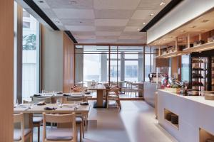 un ristorante con tavoli, sedie e finestre di AKI Hong Kong - MGallery a Hong Kong