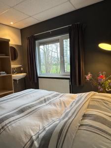 a bedroom with a large bed and a window at Villa 't Boshuys - a private and green location for families or friends up to 16 guests in Den Ham