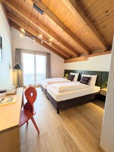 a large bedroom with two beds and a desk at Hotel Sonnwendhof Engelberg in Engelberg