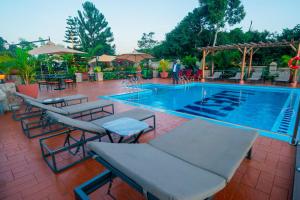 a large swimming pool with chairs and tables and umbrellas at The Lakeside in Entebbe
