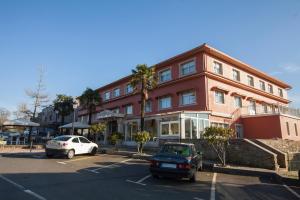 a large red building with cars parked in a parking lot at Hotel Garcas in Lavacolla