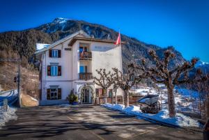 a large white building with trees in front of a mountain at Hotel Grischuna Filisur in Filisur