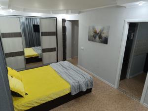 a bedroom with a yellow bed and a mirror at Современные апартаменты в центре города in Ustʼ-Kamenogorsk