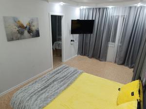 a bedroom with a bed and a flat screen tv at Современные апартаменты в центре города in Ustʼ-Kamenogorsk
