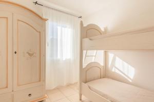 a white bedroom with a bunk bed and a window at Baia Bianca Apartments Sardinia in Baja Sardinia