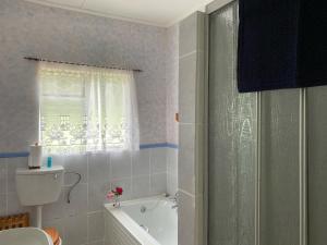 une salle de bain avec baignoire et toilettes et une fenêtre dans l'établissement Mvemve Lodge at GrootPoort, à Memel