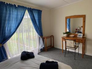 une chambre avec un lit, un bureau et une fenêtre dans l'établissement Mvemve Lodge at GrootPoort, à Memel