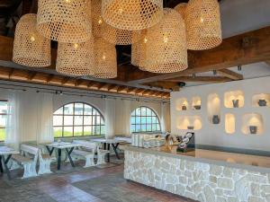 a restaurant with several chandeliers and tables and benches at GRIFID Noa in Golden Sands