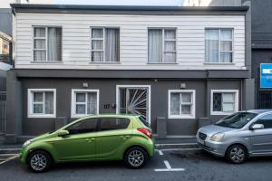 a green car parked in front of a house at Cosy and Central in Claremont in Cape Town