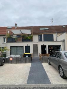 een huis met twee auto's ervoor geparkeerd bij Appartement 15 min Disney Paris in Coutevroult