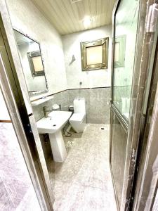 a bathroom with a sink and a toilet and a mirror at جود ان للشقق الفندقية in Aţ Ţunḑubāwī