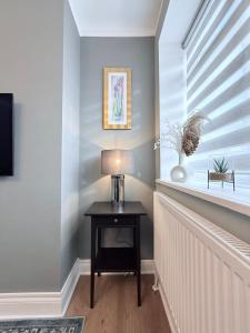 Zimmer mit einem Tisch mit einer Lampe und einem Fenster in der Unterkunft StayLondon - Sleeps 5 with Free Parking - best for Holiday, Concerts or Matches in London