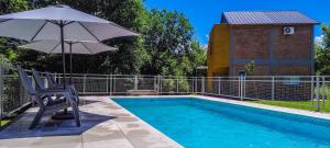 a chair and an umbrella next to a swimming pool at Cabañas Madre Sierra in Santa Rosa de Calamuchita