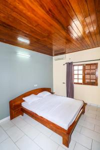 a bed in a room with a wooden ceiling at Villa Nath - Kribi in Elabi