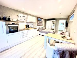 a large kitchen with white cabinets and a table at Bungalow Seeblick Am Achterwasser in Ueckeritz